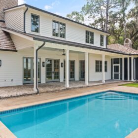 A lovely rectangular pool next to a new white house with cedar shingles and farmhouse look to it. French doors lead out to the pool from the ground floor. The pool is finished with Diamond Brite Blue by Golden Seas Outdoors.